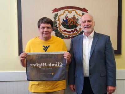 a photo of Paul Kreider standing next to Hunter Turner, who is holding the 'Climb Higher banner'